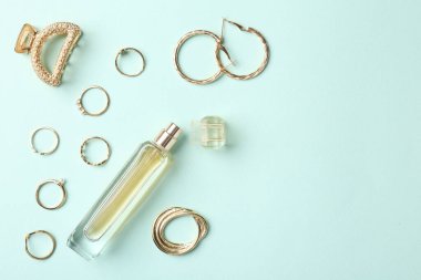 Stylish accessories and perfume on light blue background, flat lay. Space for text