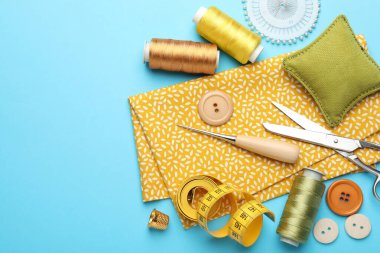 Açık mavi arka planda farklı dikiş malzemeleri, düz bir zemin. Metin için boşluk
