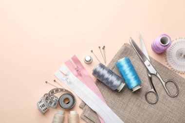 Açık pembe arka planda farklı dikiş malzemeleri, düz bir zemin. Metin için boşluk
