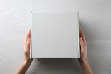 Beyaz ahşap arka planda boş karton kutulu kadın, üst manzara. Tasarım için model