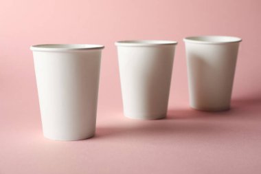 Pembe arka planda kağıt bardaklar, yakın plan. Tasarım için model