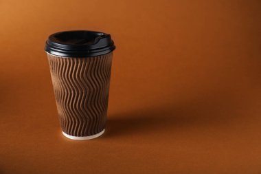 Kahverengi arka planda bir kağıt bardak. Tasarım için model