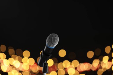 Mikrofon siyah arkaplanda bulanık ışıklarla duruyor, mesaj için yer var. Bokeh etkisi