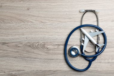 Tıbbi turizm. Stetoskop ve uçak modeli açık ahşap arka plan, üst manzara. Metin için boşluk
