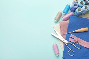 Açık mavi arka planda farklı dikiş malzemeleri, düz bir zemin. Metin için boşluk