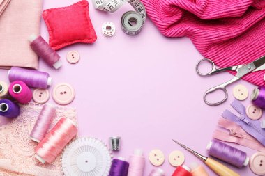 Leylak arka planında farklı dikiş malzemelerinin çerçevesi düz. Metin için boşluk