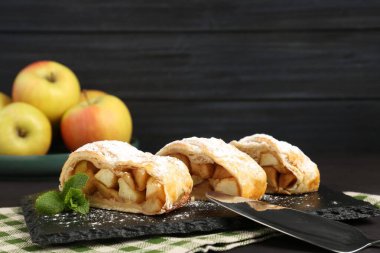 Lezzetli elmalı turta parçaları pudra şekeri ve siyah masada nane şekeri, yakın plan.