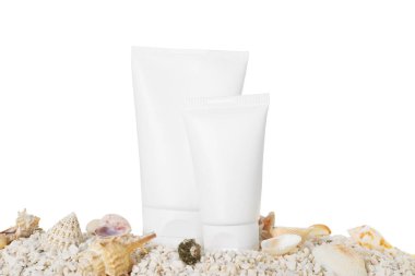 Güneş koruma tüpleri ve çakıl taşları beyaz arka plana karşı deniz kabukları