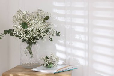 Evdeki masasında okaliptüs dalları vazoda ve dergiler olan güzel gypila çiçekleri. Metin için boşluk