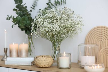 Güzel çikila çiçekleri, okaliptüs dalları, yanan mumlar ve evde klozet üzerine kitaplar.