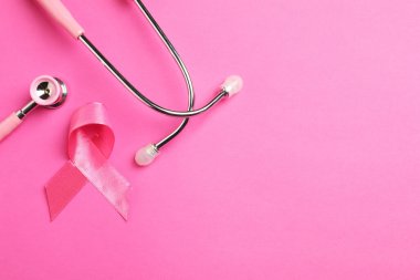 Göğüs kanseri farkındalığı. Renkli arka planda pembe kurdele ve steteskop, düz konum. Metin için boşluk