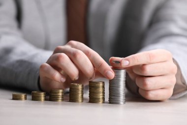 Beyaz ahşap masadaki bozuklukların üzerine para koyan adam, yakın plan.