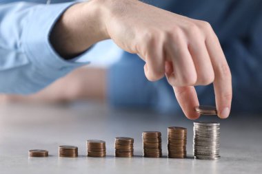 Adam açık gri masadaki bozuklukların üzerine para koyuyor, yakın plan.