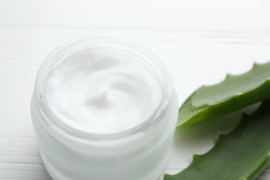 Beyaz ahşap arka planda krema ve aloe yaprakları, yakın plan