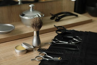 Berber dükkanında, açık ahşap masanın üzerinde birçok farklı berber aleti var.