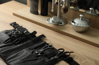 Berber dükkanında, açık ahşap masanın üzerinde birçok farklı berber aleti var.