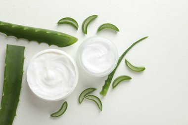 Aloe vera özütüyle nemlendirici krem ve beyaz desenli arka planda yapraklar.