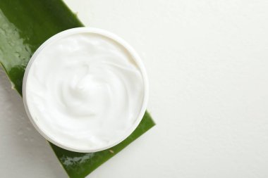 Aloe vera özütüyle nemlendirici krem ve beyaz arka planda yaprak kesimi, üst manzara. Metin için boşluk