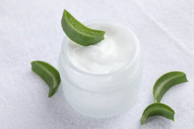 Aloe vera özütüyle nemlendirici krem ve beyaz havluyla kesilen yapraklar, yakın plan.