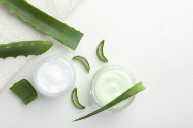 Aloe vera özütüyle nemlendirici krem, beyaz desenli arka planda yaprak ve havlu, düz uzanma