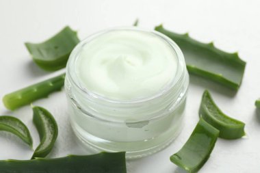 Aloe vera özütüyle nemlendirici krem ve beyaz desenli arka planda yapraklar, yakın plan