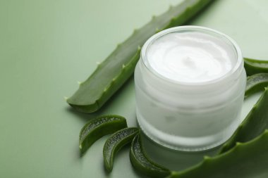 Kavanozda aloe vera özütüyle nemlendirici krem ve yeşil arka planda yapraklar, yakın plan. Metin için boşluk