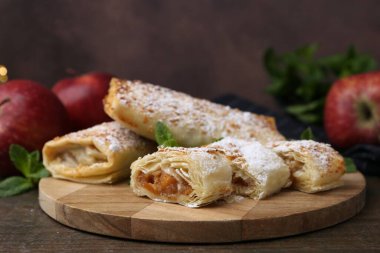 Ahşap masada pudra şekeri, nane ve meyveli elmalı turtalar, yakın plan.