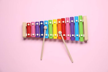 Pembe arka planda tokmakları olan renkli oyuncak ksilofon, üst görünüm
