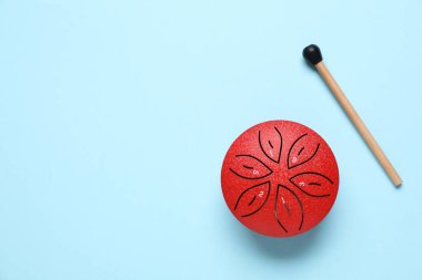 Açık mavi arka planda tokmaklı oyuncak dilli davul, düz yatıyordu. Metin için boşluk