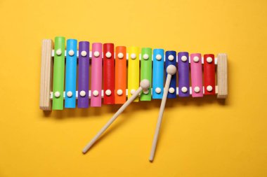 Sarı arka planda tokmakları olan renkli oyuncak ksilofon, üst görünüm