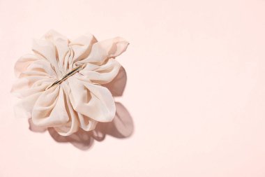 Soluk pembe arka planda bir saç tokası, üst manzara. Metin için boşluk