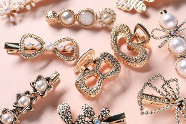 Soluk pembe arka planda farklı saç tokaları, düz yatış.