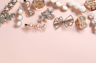 Soluk pembe arka planda farklı saç tokaları, düz yatış. Metin için boşluk