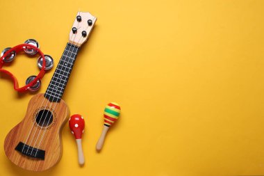 Turuncu arka planda farklı oyuncak müzik aletleri, düz yatış. Metin için boşluk