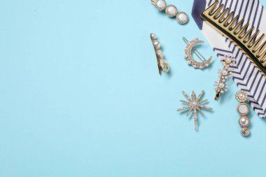 Açık mavi arka planda farklı saç tokaları, tarak ve mendil, düz yatış. Metin için boşluk