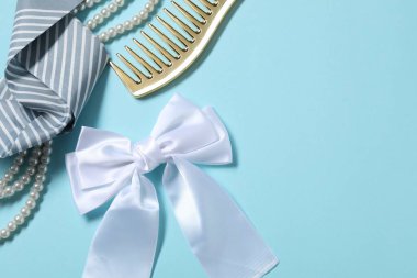 Güzel saç fiyongu, tarak, inci kolye ve açık mavi arka planda mendil, düz yatış. Metin için boşluk