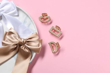 Pembe arka planda güzel saç fiyonkları ve klipsleri, düz yatış. Metin için boşluk