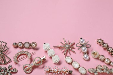 Different hair clips on pink background, flat lay. Space for text