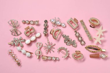 Different hair clips on pink background, flat lay