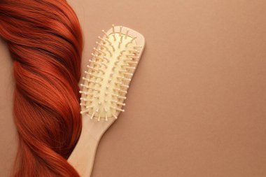 Tahta fırça ve bej arka planda bir tutam saç, üst manzara. Metin için boşluk