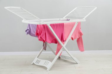 Gri duvarın yanında temiz çamaşırları olan kuru askı.