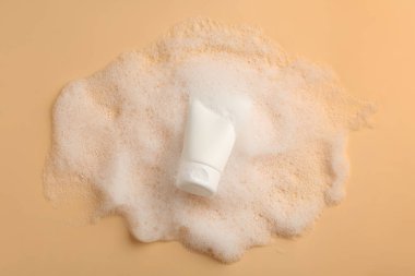 Bej arka planı köpüklü kozmetik ürün tübü, üst görünüm