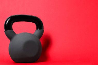 Kırmızı arka planda bir tane kettlebell. Metin için boşluk
