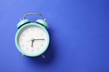 Mavi arka planda bir turkuaz alarm saati, üst manzara. Metin için boşluk