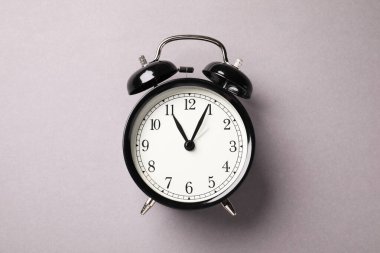 Açık gri arkaplanda bir siyah alarm saati, üst görünüm
