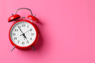 Pembe arka planda kırmızı alarmlı saat, üst manzara. Metin için boşluk