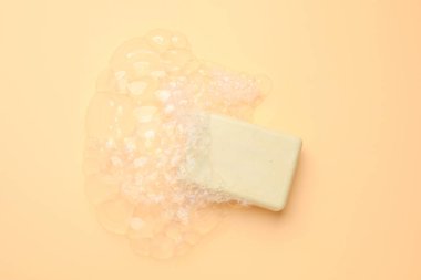 Şeftali arka planında köpük olan sabun çubuğu, üst görünüm