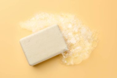 Sarı zemin üzerinde köpük olan sabun çubuğu, üst görünüm