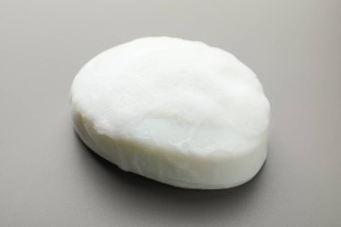 Gri arkaplanda köpük olan sabun çubuğu, yakın plan.