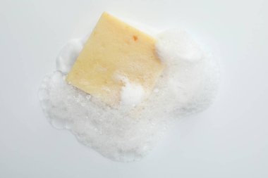 Beyaz arka planda köpük olan sabun çubuğu, üst görünüm